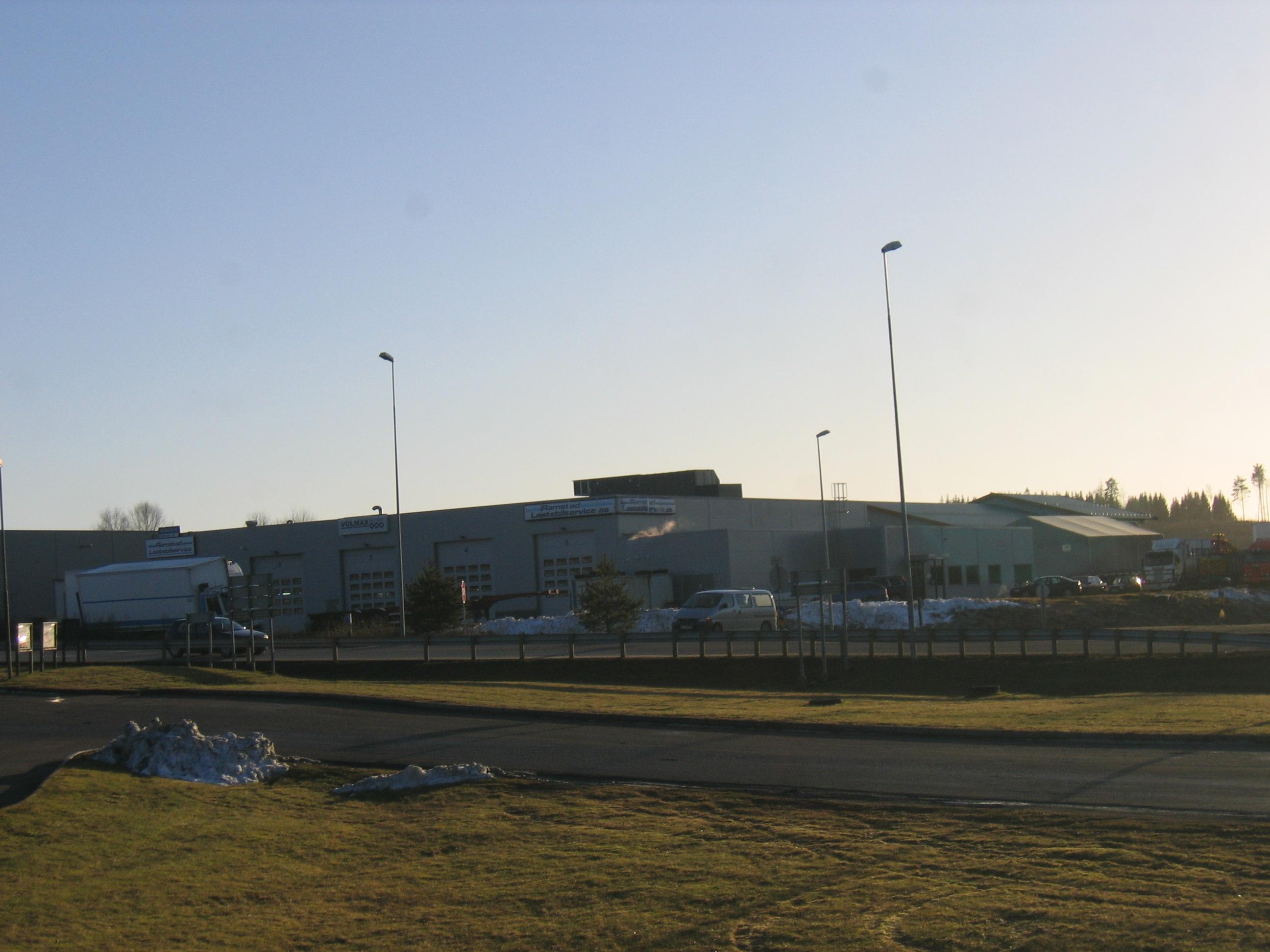 En stor bygning med parkerte biler og gatebelysning under en klar himmel.