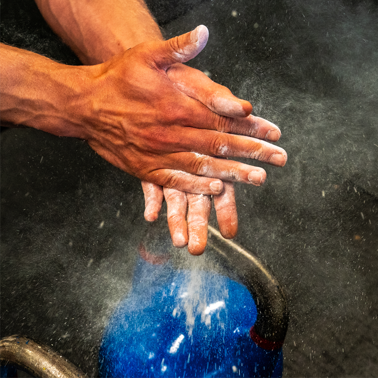 Hender som gnir seg sammen med magnesiumpulver før trening med kettlebell.