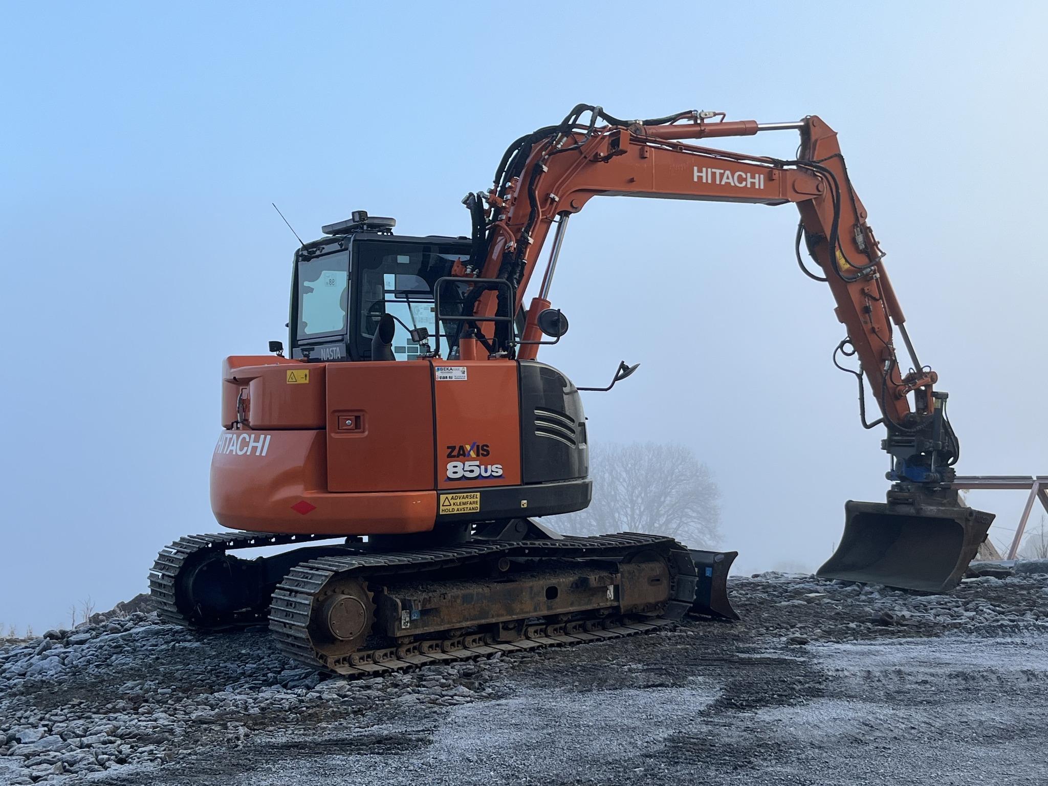 Gravemaskin fra Hitachi står på en byggeplass i tåke, klar til å begynne arbeidet.