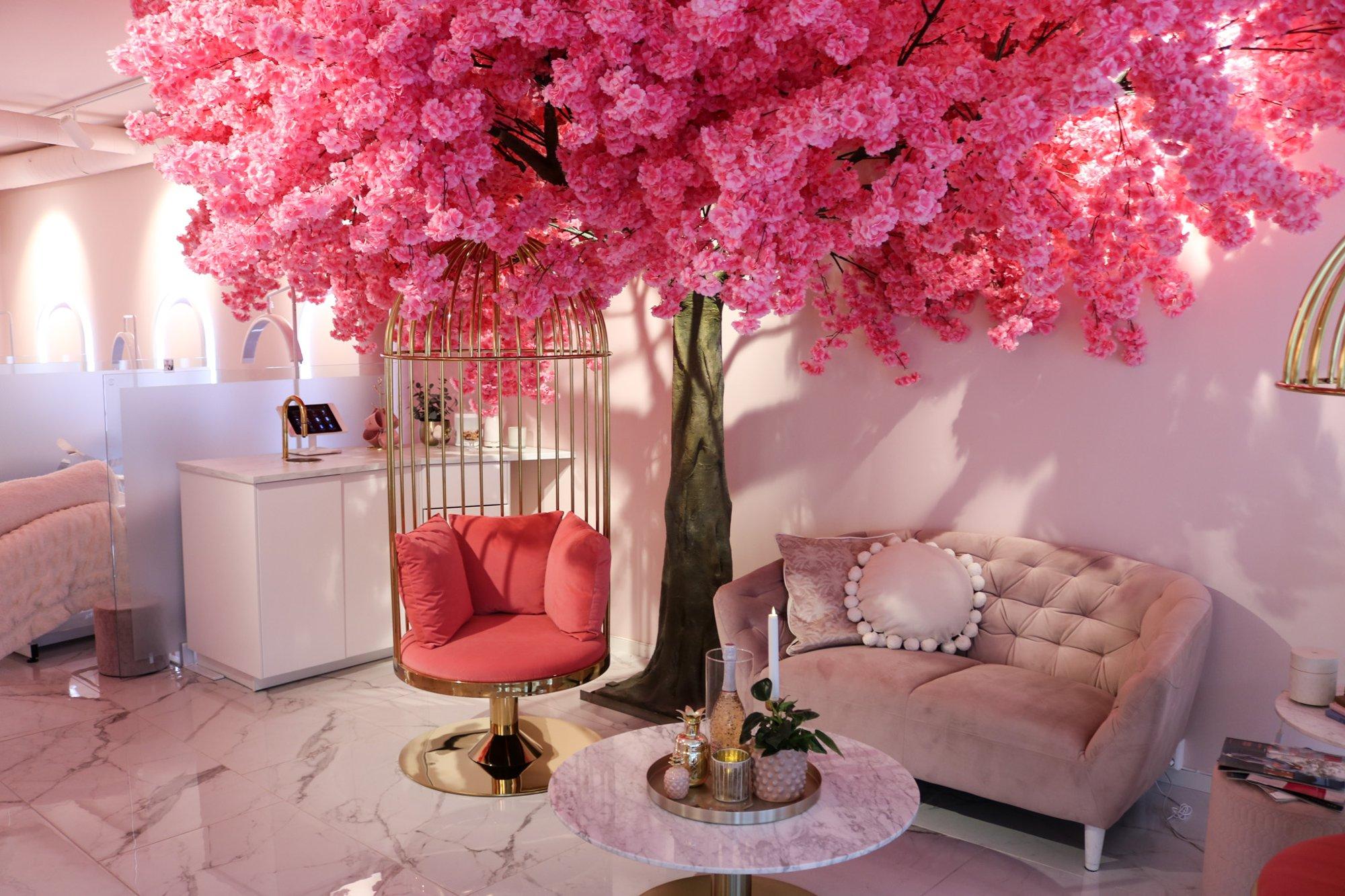 Romantisk interiør med rosa kirsebærtre, komfortable møbler og elegant bord i en moderne stue.