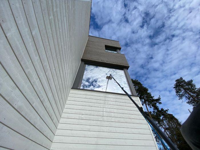 Moderne bygning med speilvegg og himmel i bakgrunnen, sett fra bakkenivå.