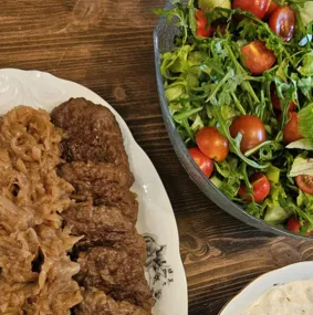 Bilde av en tallerken med kjøttdeig og surkål, ved siden av en bolle med frisk salat og cherrytomater.