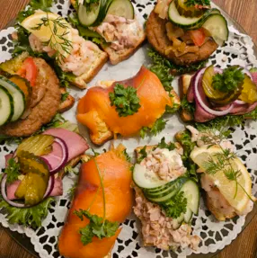Et fat med ulike smørbrød, inkludert laks, tunfisk, grønnsaker og dill, ser fristende ut.