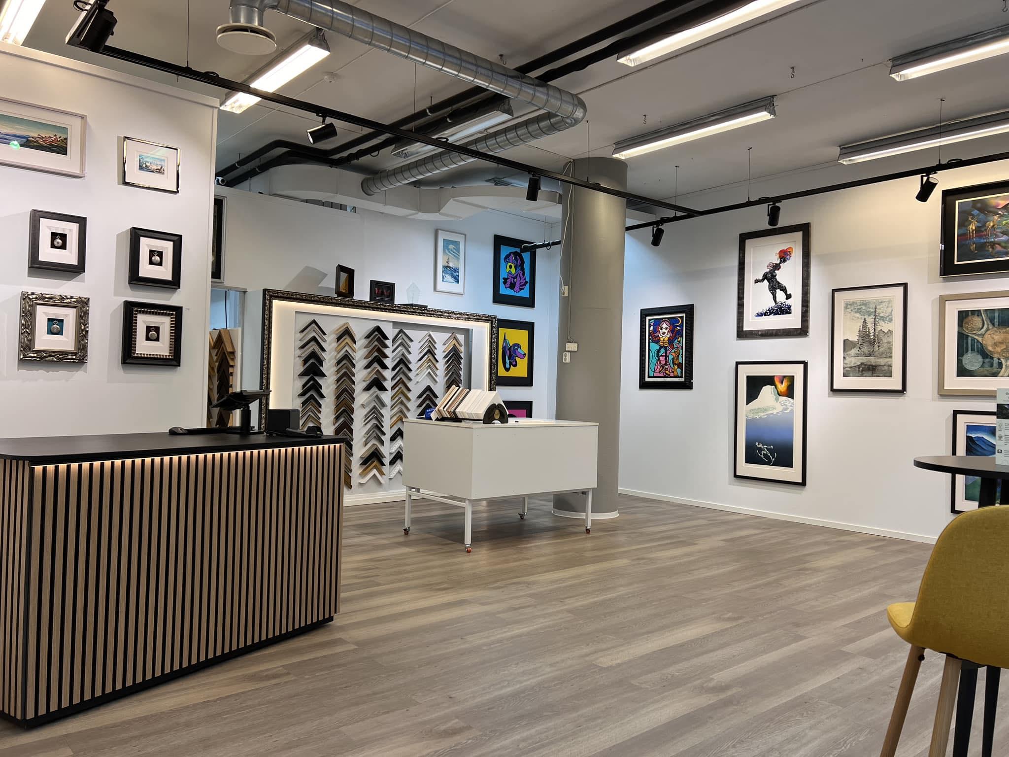 Moderne kunstgalleri med rammer, malerier på veggene og en resepsjonsdisk i forgrunnen.