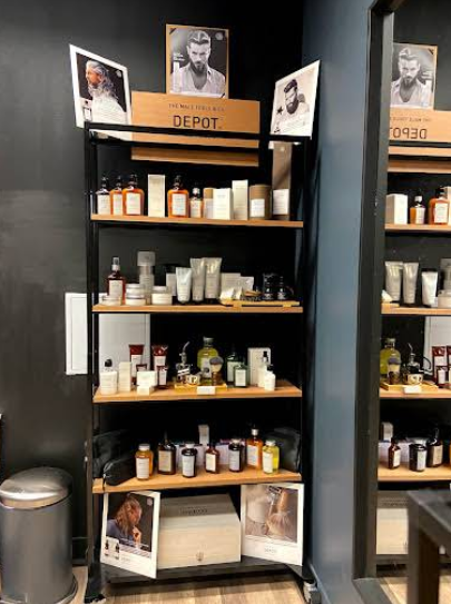 Hyller med groomingprodukter fra merket Depot, inkludert kremer, oljer og parfymer, i en moderne salong.