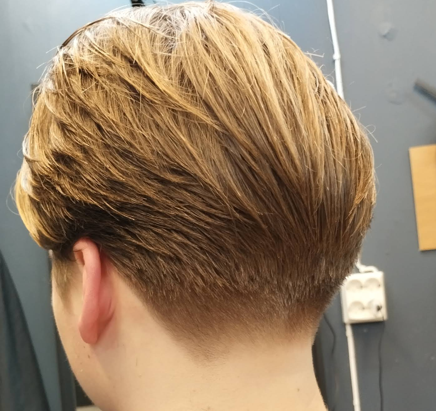 En moderne herrefrisyre med kort bak og lengre hår på toppen, i lys brunt og blondt.
