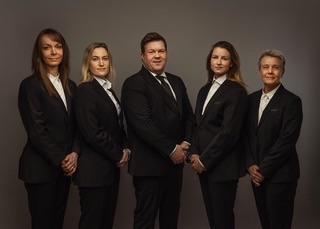 Fem profesjonelle personer i dress står sammen foran en nøytral bakgrunn.