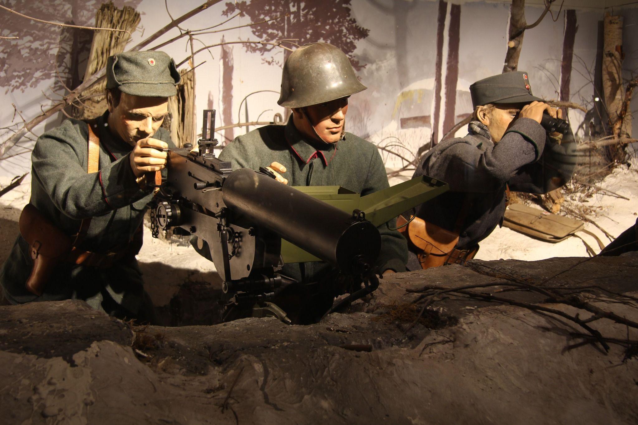 Tre soldater i en skyttergrav, med en maskingevær og militærutstyr, i en historisk krigsscene.