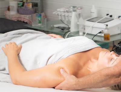 En kvinne får massasje på en behandlingsbenk i et moderne spa med utstyr i bakgrunnen.