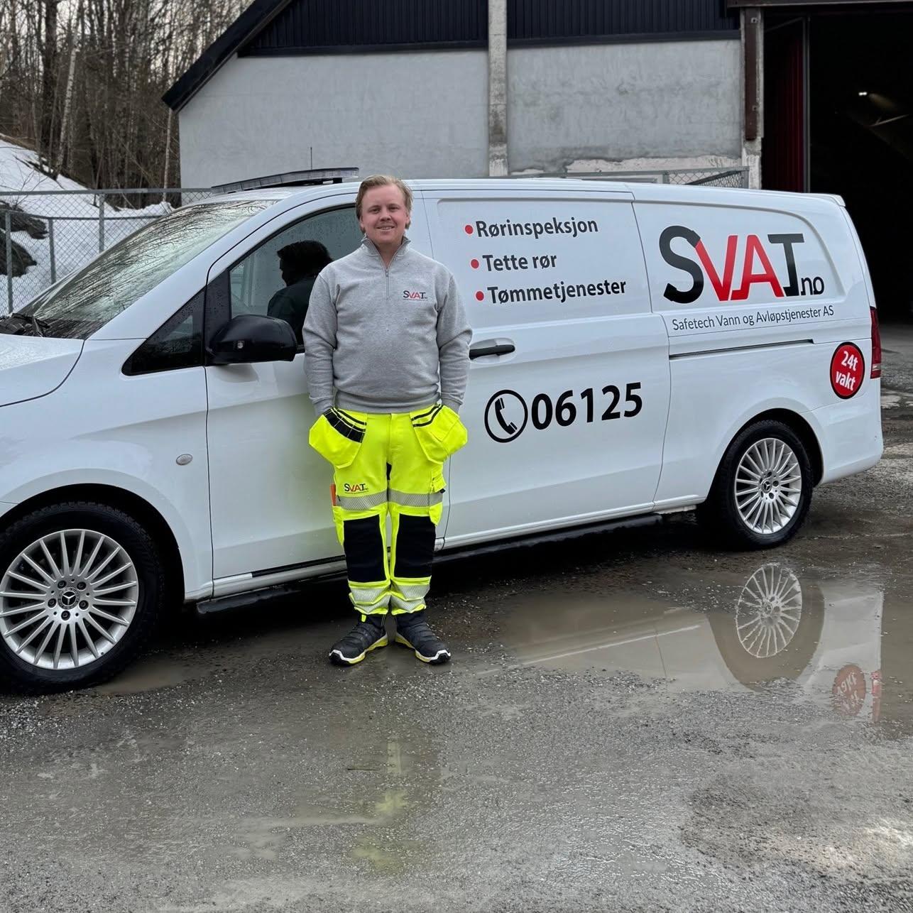 En person i arbeidsklær står foran en varebil med logoen SVAT.no, på en grusvei.
