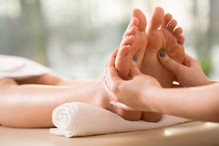 En person får fotmassasje med fokus på tærne og sålene, med en hånd som masserer foten.