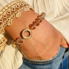 Et nærbilde av en hånd med en elegant armbånd laget av perler og en glitrende ring.