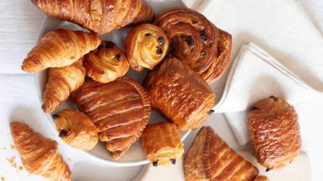 En tallerken med forskjellige bakverk, inkludert croissanter, kanelsnurrer og fylt deig.