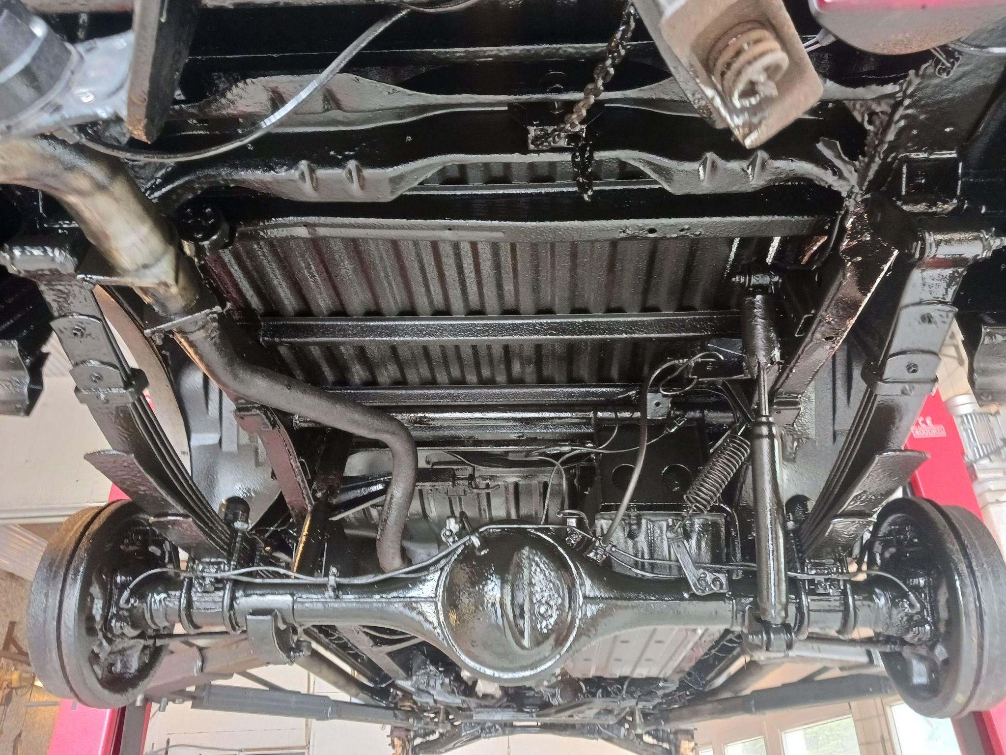 Bilde av underside av bil med detaljerte komponenter som aksel, fjærer og chassis.