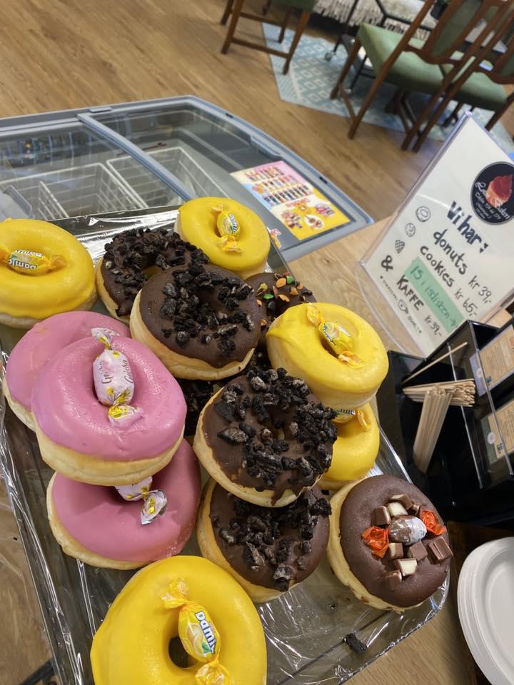 Fargerike donuts med sjokolade, krem og godteri på et fat i en kafé.