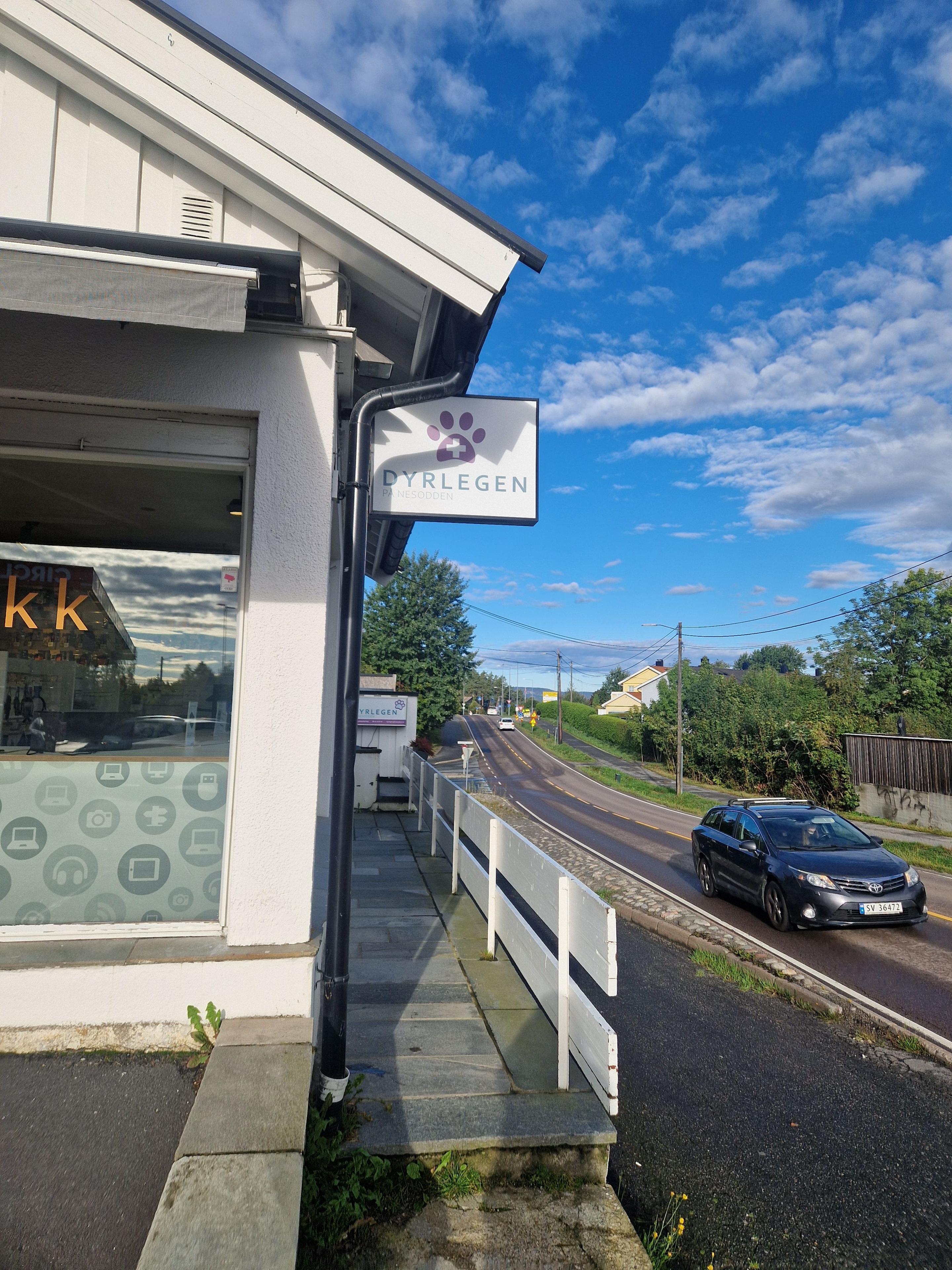 Kaféen med skiltet "Kaffehuset" ved veien, med en bil som kjører forbi under en blå himmel.