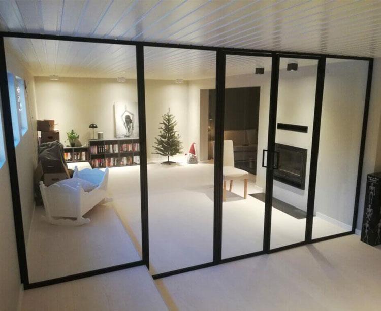 Moderne stue med glassvegger, peis, julegran og komfortable møbler i et lyst rom.