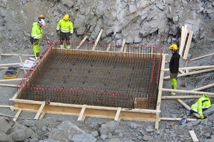 Byggearbeidere som jobber med armering av en betongfundament i en steinbrudd.