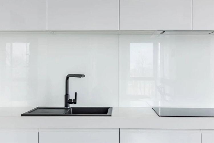 Moderne kjøkken med hvite skap, svart vask og induksjonsplate i minimalistisk design.
