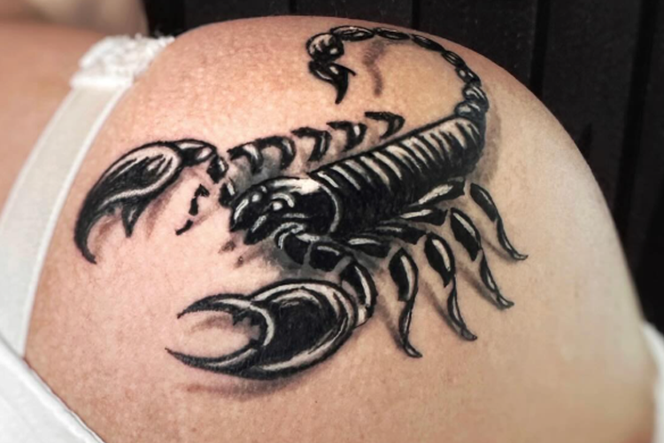 Tatovering av en skorpion på skulderen, med detaljerte linjer og skyggelegging.