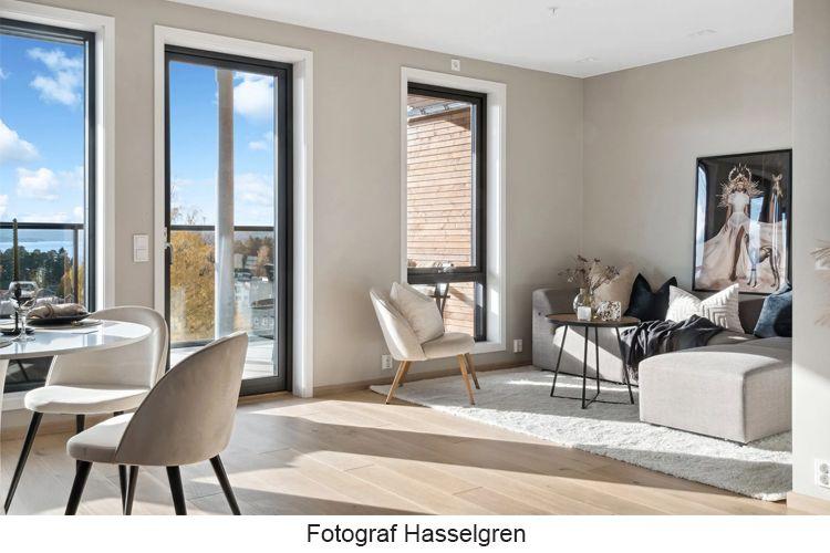Moderne stue med store vinduer, lys innredning og en komfortabel sofa i et nybygd hjem.