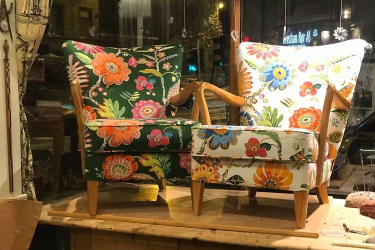 To stoler med fargerike blomsterdesign i et vindu, plassert på et trebord.