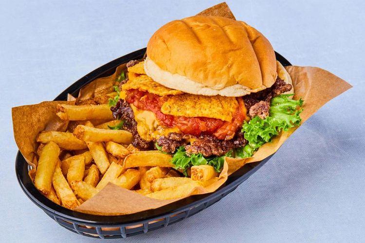 En saftig hamburger med sprø kylling, salat og tomat, servert med gyldne pommes frites i en kurv.