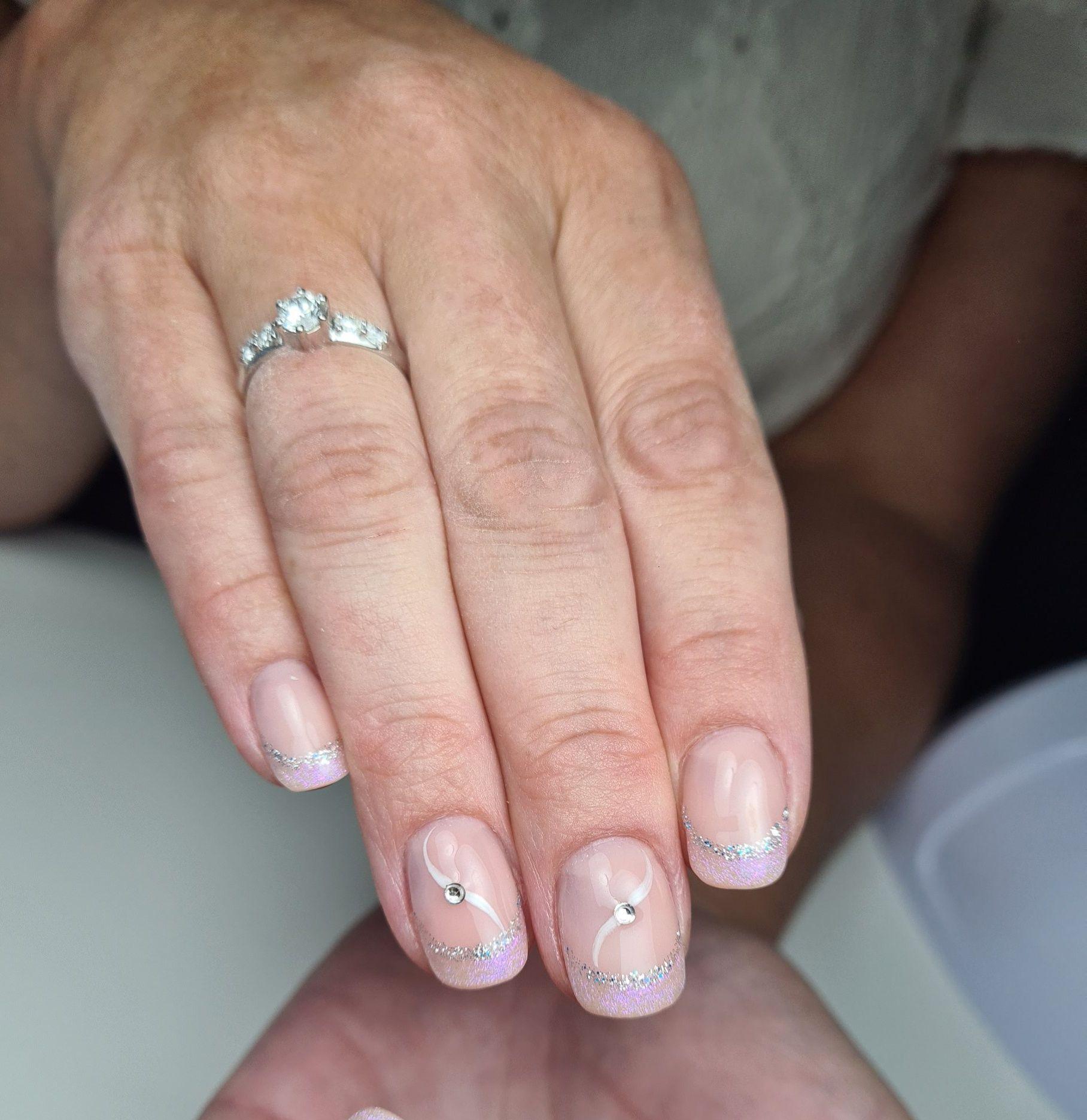 Hånd med velpleide negler, lyslilla fransk manikyr og en diamantring på fingeren.