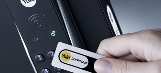 En hånd holder et Yale adgangskort foran en elektronisk lås med lysindikatorer.