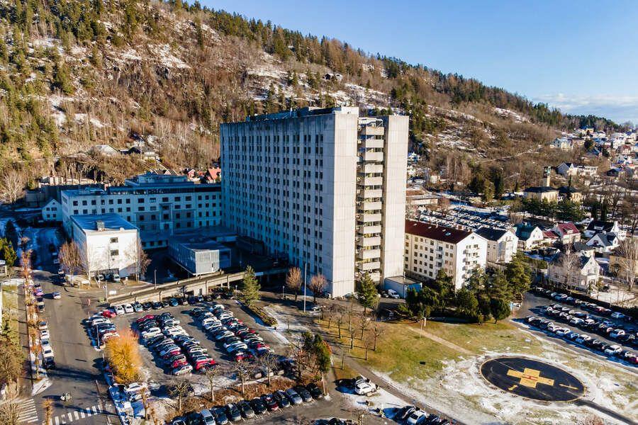 Et stort hotellbygning med flere etasjer, omgitt av parkeringsplasser og fjell i bakgrunnen.