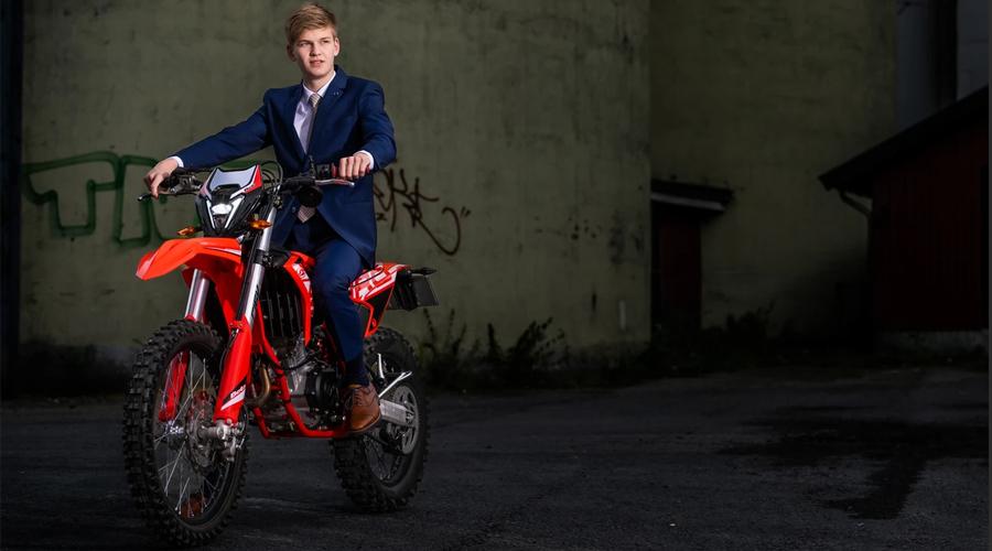 Ung mann i dress som sitter på en rød motocross-sykkel i en urban setting.