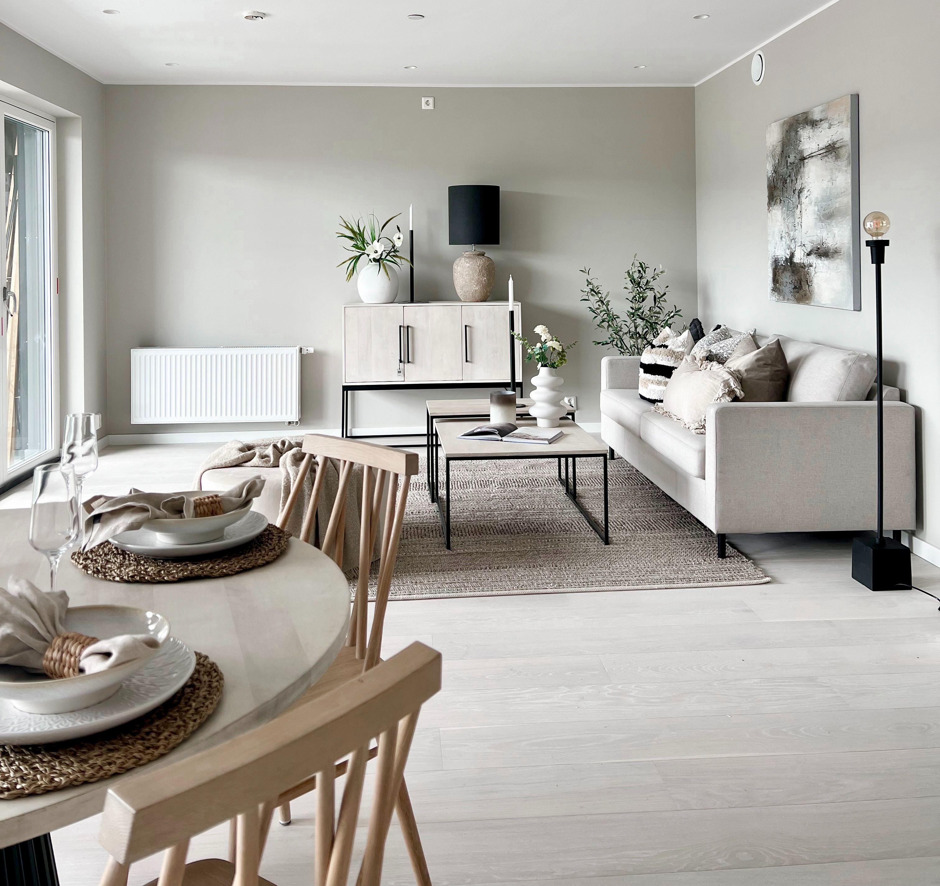 Moderne stue med grå vegger, sofa, bord og spisebord med dekorative detaljer og planter.
