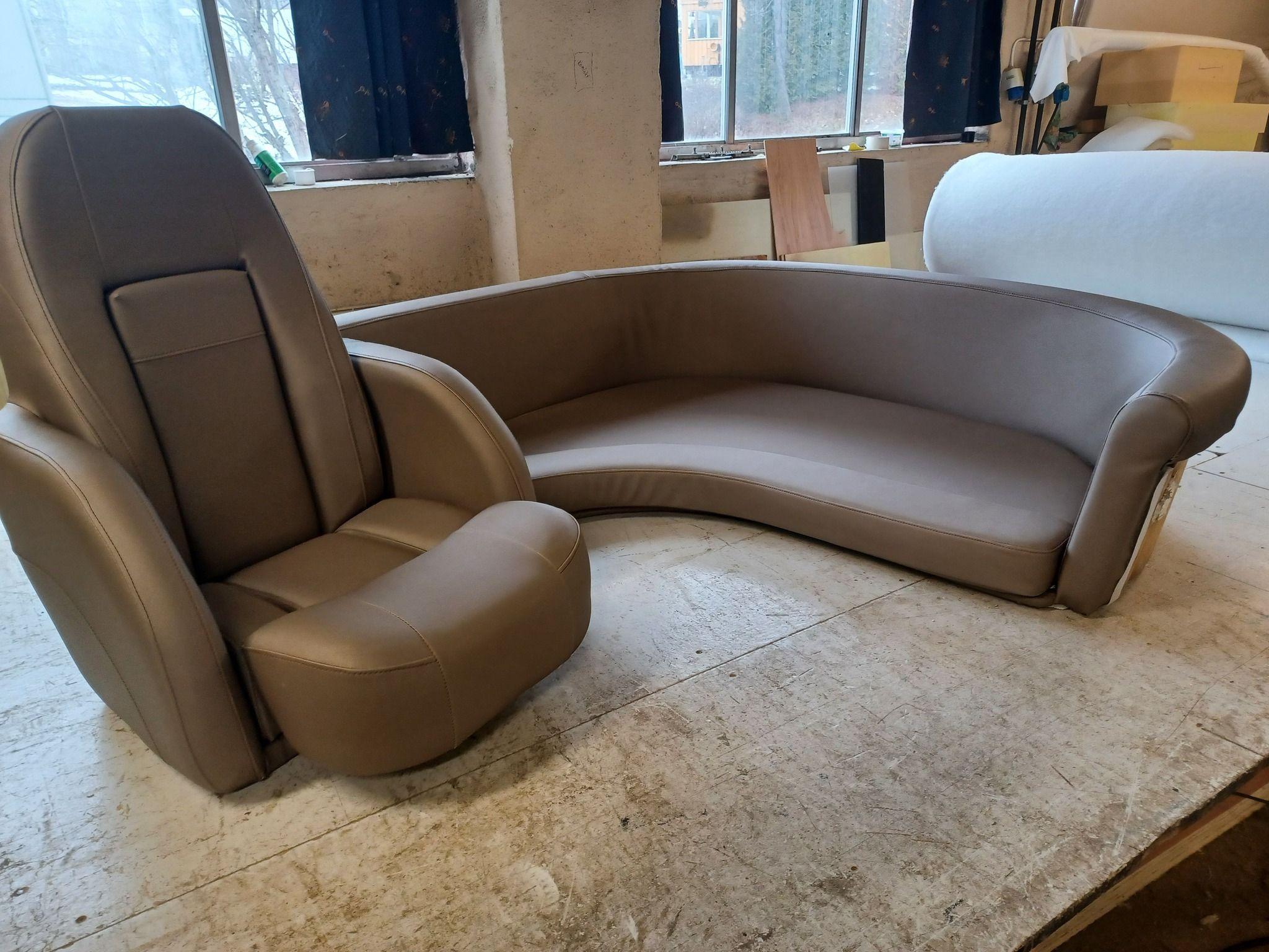 Moderne sofa og lenestol i brunt skinn, plassert på et lyst rom med vinduer.