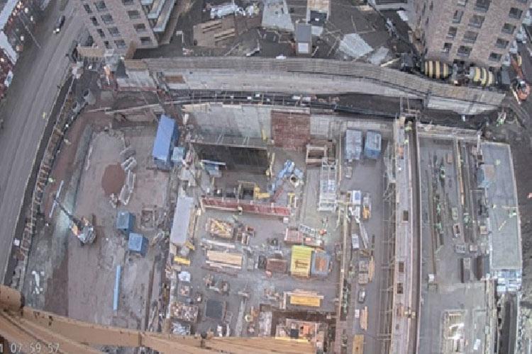 Byggeplass med kraner, byggeutstyr og materialer i en urban setting. Arbeid pågår i flere områder.