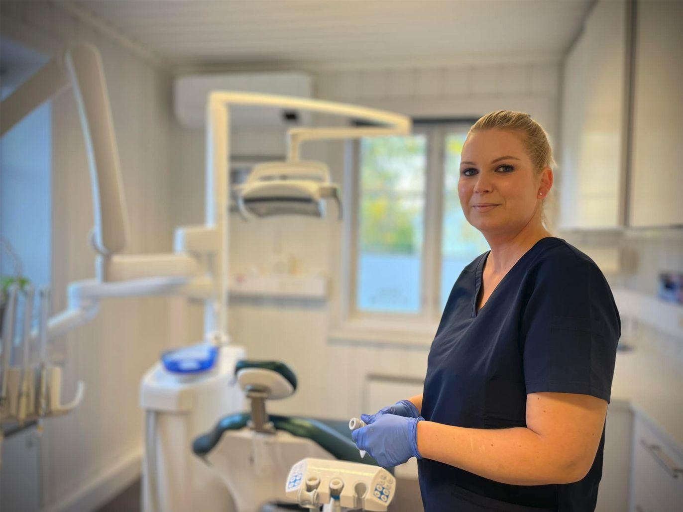 Tannlegeassistent i et moderne tannlegekontor med utstyr og vindu i bakgrunnen.