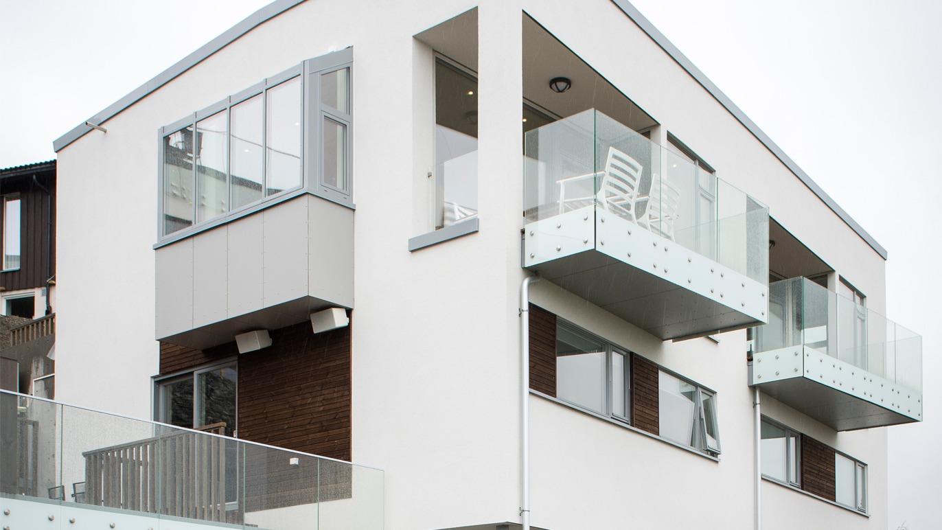 Moderne hus med balkonger og store vinduer, beliggende i et urbant område.