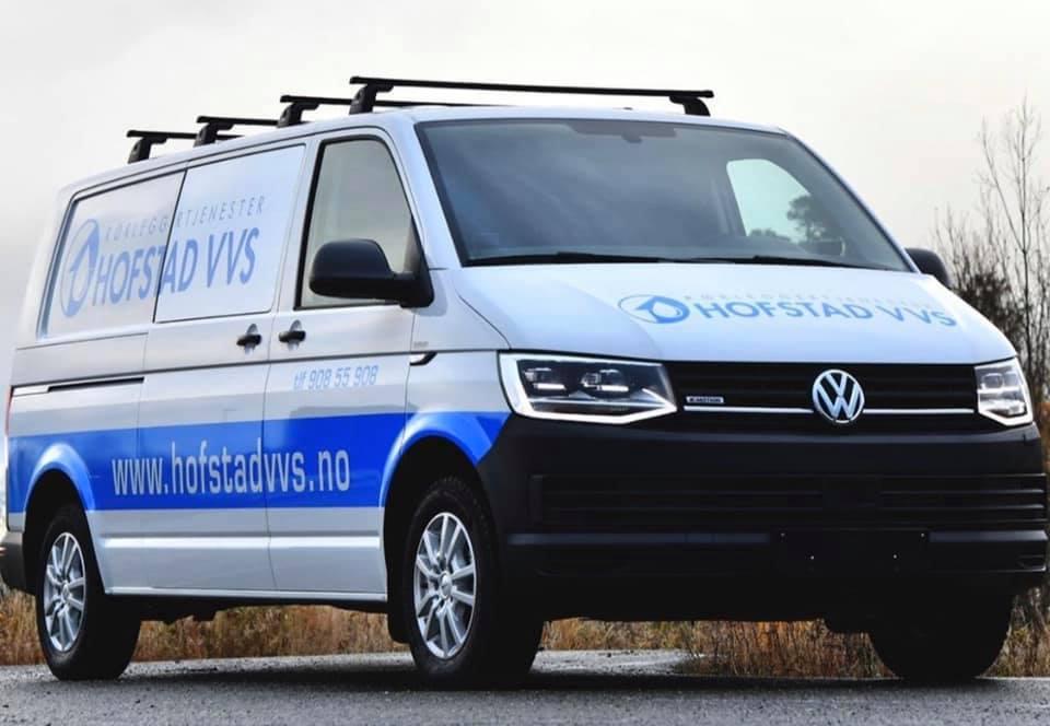 En Volkswagen varebil med logoen til Høstad VVS, parkert på en vei med natur i bakgrunnen.