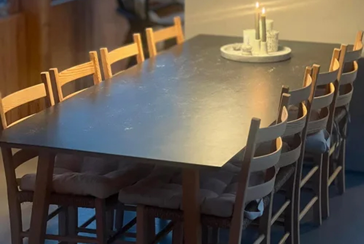 Et langt spisebord med åtte stoler, dekket med lys og en dekorativ tallerken i midten.