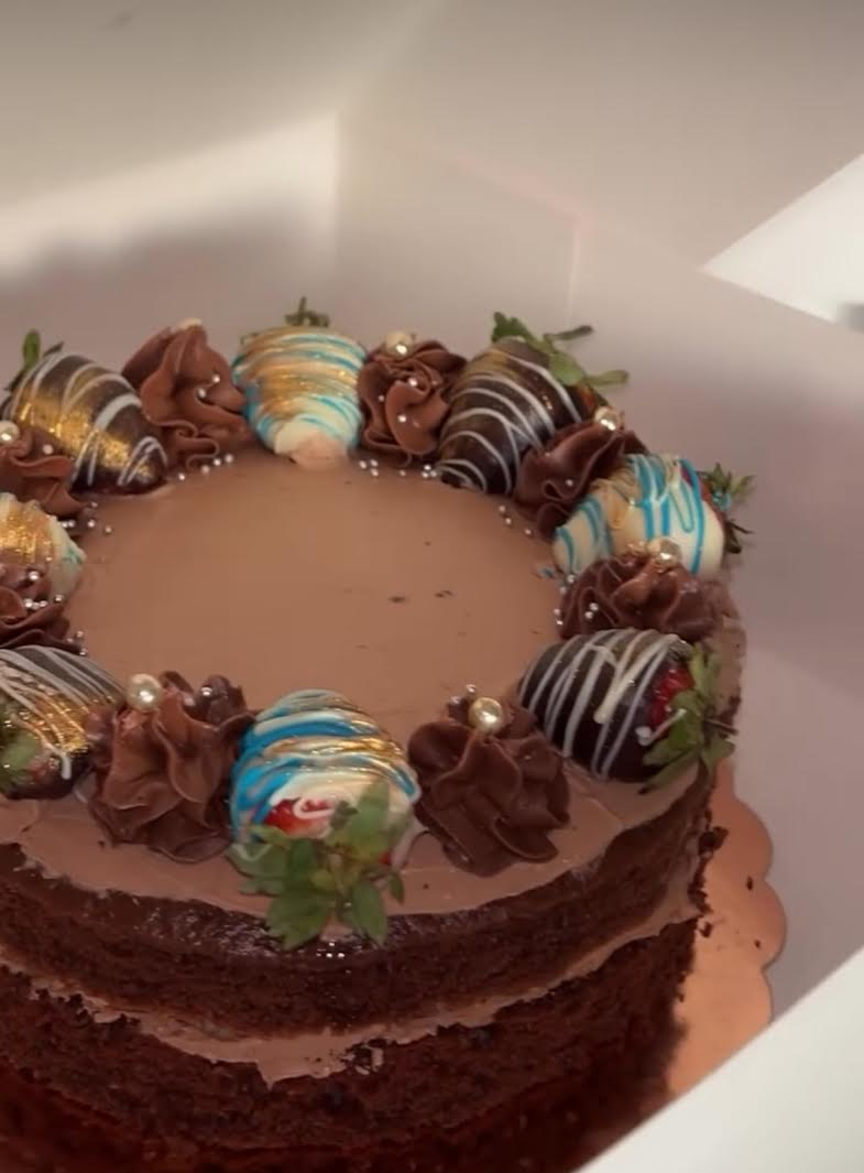 En sjokoladekake med dekorative jordbær og sjokoladefrosting, plassert i en hvit eske.