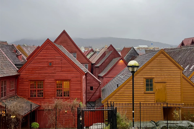 Fargerike trehus i Bergen med røde og gule fasader under en grå himmel.