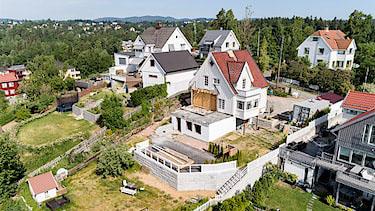 Utsikt over et boligområde med flere hus, hager og trær i bakgrunnen.