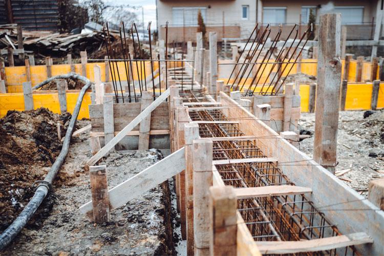 Byggeplass med betongfundament og armeringsjern i forskaling, klart for støping av fundament.
