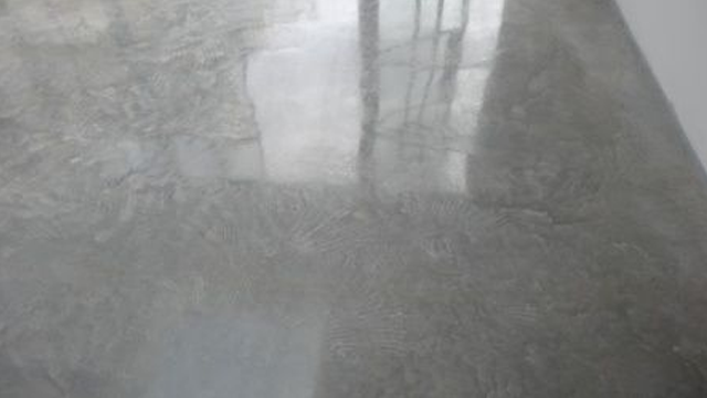 Glatte, grå betonggulv med reflekterende overflate og mønster.