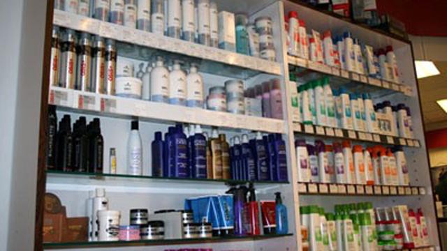Hyller med ulike hårpleieprodukter, inkludert sjampo, balsam og stylingprodukter i en butikk.