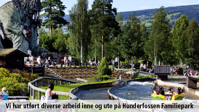 Familiepark med elv, grøntområder og besøkende som nyter solen i Hunderfossen Familiepark.
