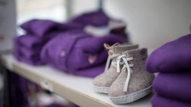 Lette, grå barneboots med hvite snører foran en hylle med lilla klær.
