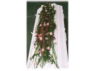 Kiste dekket med blomster og grønt, med rosa blomster og urter som pryder toppen.