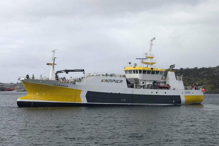 Ferge med gul og grå farge som seiler på vannet, med passasjerer om bord.