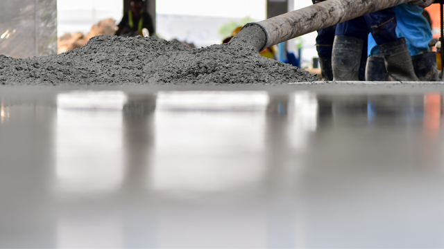 Betong helles på gulvet av arbeidere i byggeprosjekt, med fokus på den glatte overflaten.