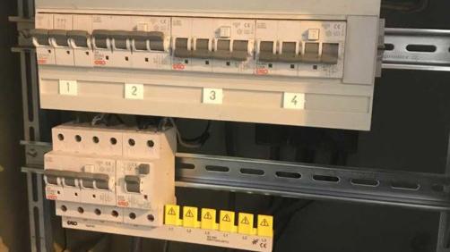 Bilde av en elektrisk tavle med sikringer og jordfeilbrytere, nummerert fra 1 til 4, i et metallskap.